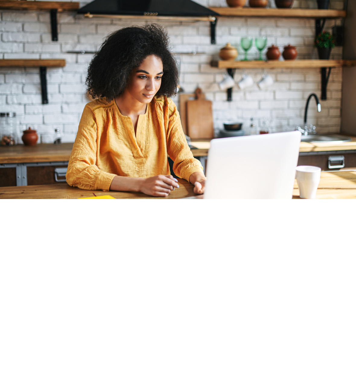 diverse young woman looking down at her laptop in her kitchen